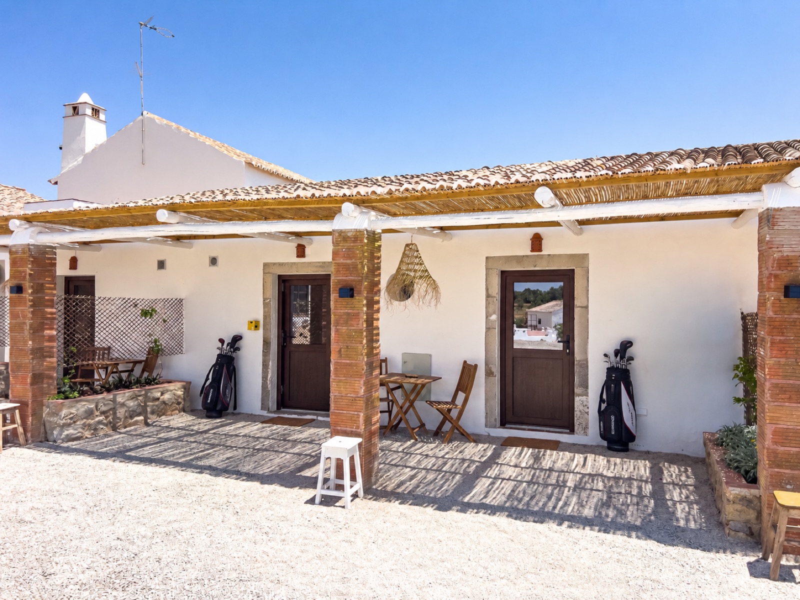 Veranda mit Schilfrohr-Pergola und Golfbags vor der Tür
